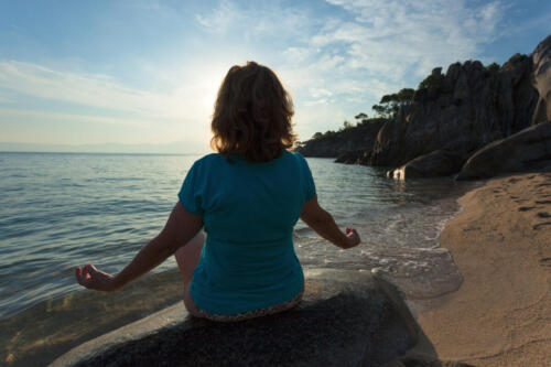 Women meditating in yoga pose on the beach at sunrise