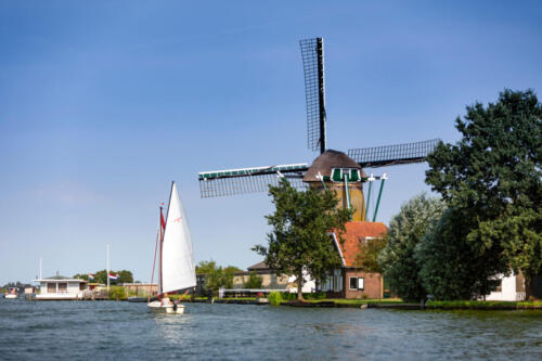 A sailboat in front of the Zwanburgermill on the Warmonderleede