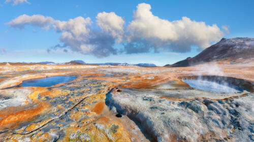 Breathtaking boiling mudpots in geothermal area Hverir and cracked ground around.